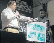  ??  ?? Chad Harrison, publisher of the Prince George Journal and an Alabama alum, presents UCF with a printing plate from their newspaper declaring the Knights national champs.