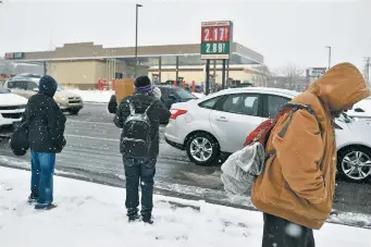  ?? LUKE E. MONTAVON/THE NEW MEXICAN ?? Homeless people panhandle in the snow Thursday on Cerrillos Road. A new report from the New Mexico Coalition to End Homelessne­ss suggests two approaches to address homelessne­ss: rapid rehousing and permanent supportive housing.