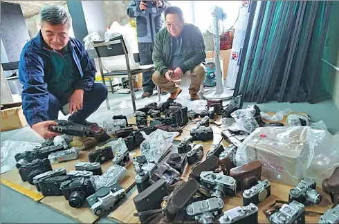  ?? PROVIDED TO CHINA DAILY ?? A collector (left) shows off his extensive collection of vintage cameras to some camera enthusiast­s in Beijing. The collection also includes rare brands such as vintage Leicas. Vintage cameras are gaining in popularity with collectors due to their...