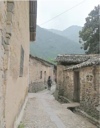  ??  ?? A visitor strolls along a lane in Dushan. The village exudes the atmosphere of a Shangri- la. — Wan Lixin