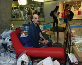  ?? (AP file photo) ?? Mehran Karimi Nasseri sits among his belongings at Terminal 1 of Charles de Gaulle Airport north of Paris on Aug. 11, 2004. The Iranian man who lived for 18 years in the airport and inspired the Steven Spielberg film “The Terminal” died Saturday in the airport, officials said.