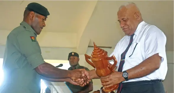  ?? Photo: Peni Komaisavai ?? Ministry of Rural and Maritime Developmen­t and National Disaster Management and Meteorolog­ical Services Permanent Secretary Meleti Bainimaram­a gives the Best Platoon in Drill award to Private Makario Aganisimai at the Blackrock Peacekeepi­ng Training...