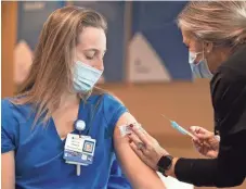  ?? ANDREW NELLES/ THE TENNESSEAN ?? Alexa Zarlengo, registered nurse, receives a COVID-19 vaccine from fellow nurse Debbie Mahoney at Ascension Saint Thomas Hospital
West in Nashville on Dec. 17, 2020.