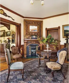  ??  ?? Homeowner Steve Arment, an accomplish­ed woodworker, created the mantel and fireplace surround from elm wood, pairing the new work to an 1880s hand-carved ash mirror from San Francisco. Art Nouveau tiles surround an antique English coal-stove insert. The door leads to the master bedroom. The parlor fireplace had been walled up, windows shot out by vandals. “We considered that the house might be too far gone,” admit the owners.