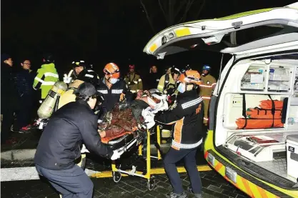  ?? —AFP ?? SEOUL: This picture shows an injured Buddhist monk who set himself on fire being carried into an ambulance in Seoul.