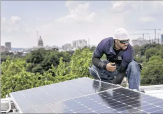  ?? LAURA SKELDING / AMERICAN-STATESMAN ?? Dorian Cunningham installs conduit for wiring the solar panels on the rooftop of the Allen-Frazier women’s dormitory at Huston-Tillotson University in late August. University officials say that the solar array, when completed, is expected to supply 10...