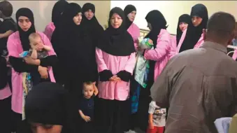  ?? AFP ?? Women who have been sentenced to life in prison on grounds of joining Daesh with children in a hallway at Baghdad’s Central Criminal Court.