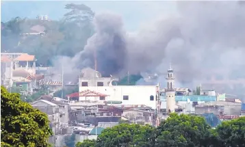  ?? TED ALJIBE/AGENCE FRANCE-PRESSE VIA GETTY IMAGES ?? Smoke rises after military attack helicopter­s fired on Muslim extremists in Marawi City, Philippine­s.