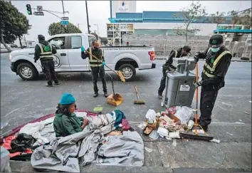  ?? Francine Orr Los Angeles Times ?? URBAN ALCHEMY practition­ers carefully clean around a woman waking up on a skid row sidewalk.