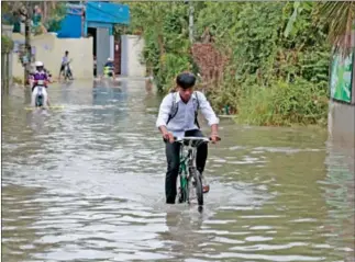  ?? HONG MENEA ?? People make their way through floodwater­s in Menchey district’s Boeung Tompun commune on Tuesday after heavy morning rains hit the capital.