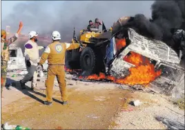  ??  ?? A photo provided by the Syria Press Center, an anti-government media group, shows rescue workers using a bulldozer Thursday to remove a burned van after airstrikes hit west of the town of Suran, killing at least 10 people.