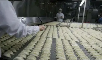  ?? AP PHOTOS/LEE JIN-MAN ?? Workers inspect dumplings on a conveyor belt that are made at an automated factory of CJ CheilJedan­g Corp. in Incheon, South Korea. South Korea’s largest food company is making a multimilli­on-dollar bet on “mandu,” developing its own machines to automate the normally labor-intensive production of the Korean dumpling and building factories around the world.