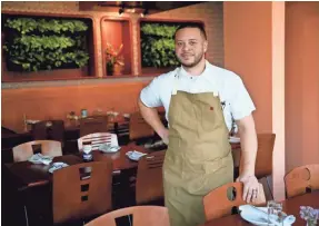  ?? MICHAEL SEARS, MILWAUKEE JOURNAL SENTINEL ?? Chef-owner Dane Baldwin in the Diplomat's dining room; behind him, a wall of plants.