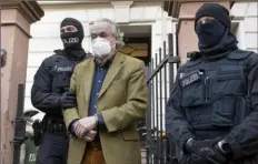  ?? Dpa via AP ?? Masked police officers lead Heinrich XIII Prince Reuss, center, to a police vehicle during a raid Wednesday against socalled “Reich citizens” in Frankfurt, Germany.