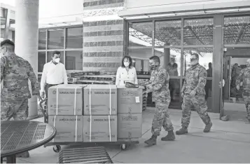  ??  ?? Marco Lopez and Sharon Harper watch as Arizona National Guard members haul away PPE shipment.