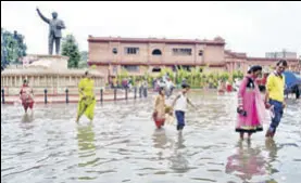  ?? SAMEER SEHGAL/HT ?? WRINGING WET People walking on a waterlogge­d Heritage Street in Amritsar.