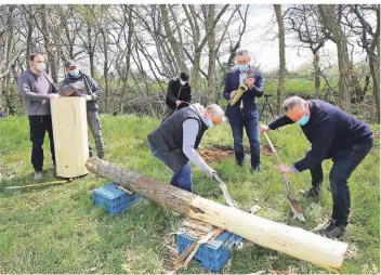  ?? RP-FOTO: FISCHER ?? André Deckers (3.v.r.) baute mit Hilfe von Freunden eine seiner speziellen Bienenbeha­usungen hinter der Gaststätte Thiesen in Bönninghar­dt auf. Saxophonis­t Eike von der Leyen (2.v.r.) begleitete die Aktion musikalisc­h.