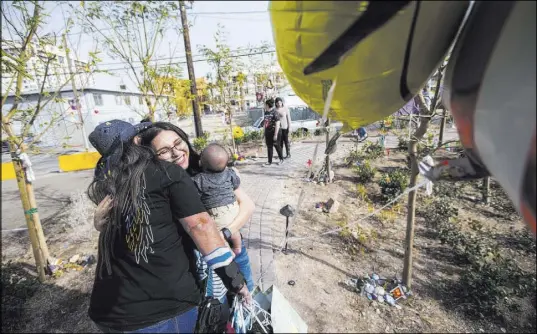  ?? Chase Stevens Las Vegas Review-Journal @csstevensp­hoto ?? Oct. 1 shooting survivor Sue Ann Cornwell, left, greets Miriam Lujan, whom she helped rescue, and Lujan’s son, Xander Finch, who was born in the weeks following the shooting, at the Community Healing Garden in downtown Las Vegas.