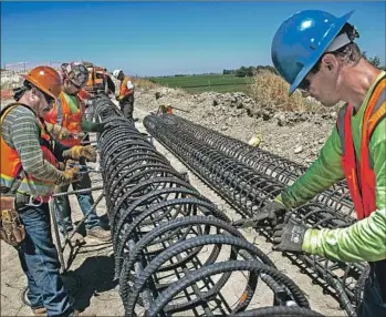  ?? California High-Speed Rail Authority ?? WORK CREWS tie rebar for a column that will be part of the abutment for the California bullet train’s Kansas Avenue overcrossi­ng south of Fresno. The project’s cost has grown to an estimated $77 billion.