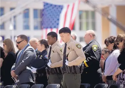  ?? MARLA BROSE/JOURNAL ?? BCSO deputy Tyler Mirabal, center, and deputy Mustafa Mudada, standing next to Mirabal, listen to the benedictio­n during the 2018 Law Enforcemen­t Memorial on Civic Plaza on Friday.