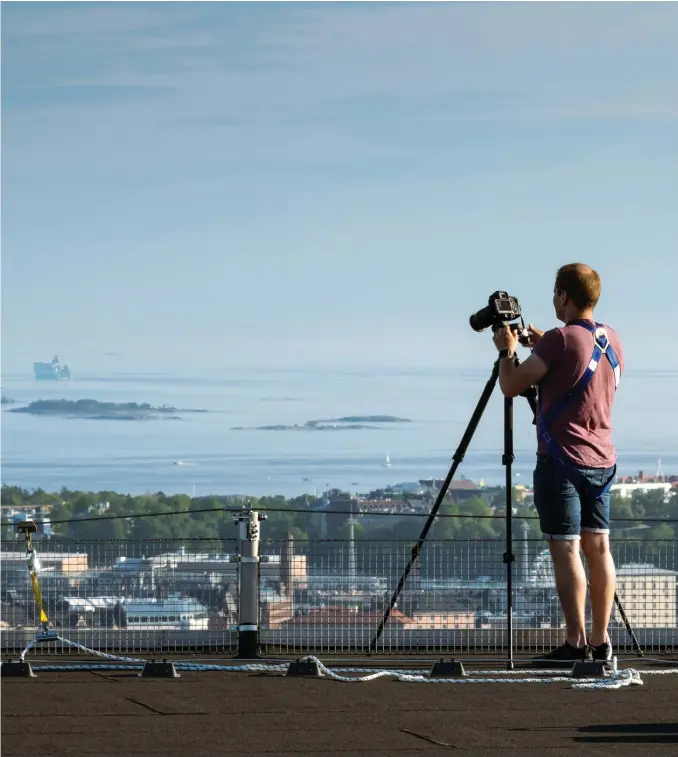  ?? FOTO: DANN PETTERSSON ?? Janne Hirvonen med Helsingfor­s i bakgrunden. På instagram är han känd som ”Majakkavah­ti” (Fyrvaktare­n). Längs med staketet löper ett smart vajersyste­m som gör att han aldrig behöver koppla sig loss.
