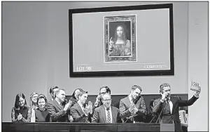  ?? AP/JULIE JACOBSON ?? Bidding representa­tives stand under a video image of Leonardo da Vinci’s Salvator Mundi after it sold for $450 million at auction Wednesday evening at Christie’s in New York.