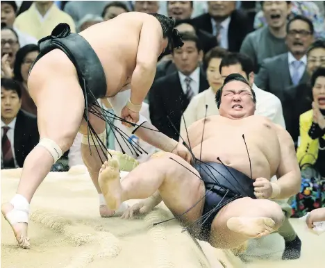  ?? JIJI PRESS/AFP/GETTY IMAGES ?? Sumo wrestler Kisenosato, right, is thrown out of the ring by Mongolia’s Harumafuji at the Spring Grand Sumo Tournament in Osaka last March. Harumafuji is accused of assaulting a younger wrestler at a bar in Tottori, Japan.