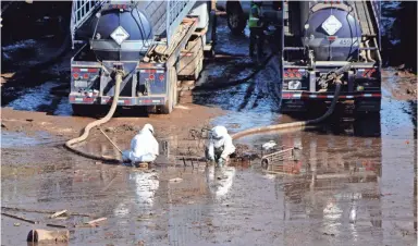  ?? TREVOR HUGHES/USA TODAY ?? Workers in hazmat suits pump out muddy water from U.S. Highway 101 at Montecito.