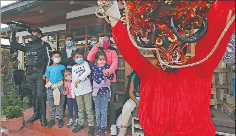  ??  ?? A family watches a person perform dressed as a devil.