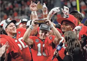  ?? JOSHUA L. JONES/ATHENS BANNER-HERALD ?? Georgia quarterbac­k Stetson Bennett raises the SEC Championsh­ip MVP trophy after the victory against LSU.