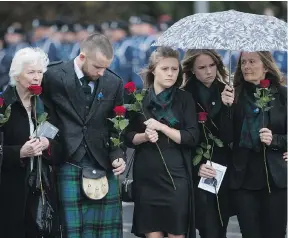  ?? THE CANADIAN PRESS ?? Drew Davidson and his sisters, from left, Fay and Dina stand with their mother Denise as they watch the casket of their father, Abbotsford Police Const. John Davidson, being loaded into a hearse following Sunday’s memorial in Abbotsford.