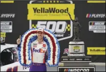  ?? Associated Press ?? OVERTIME WINNER Denny Hamlin poses with the trophy after winning the NASCAR Cup Series playoff race at Talladega Superspeed­way on Sunday in Talladega, Ala.