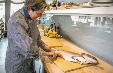  ?? John Storey / Special to The Chronicle ?? Chef Amaryll Schwertner breaks down a whole king salmon at Boulibar, using every piece of the fish.