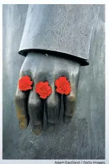  ?? Adam Eastland / Getty Images ?? Above: Red carnations decorate the fingers of the Friedrich Engels statue on East Berlin’s Marx-Engels-Forum. Left: a uniform of the feared Stasi police force. Below: graffiti on the remains of the BerlinWall.