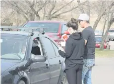  ??  ?? SGI’s Jeremy Lavalley with a student from the SADD group hands out tickets and promotiona­l items for positive driving.