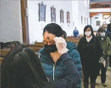  ??  ?? Right: Tammy Valerio receives her ashes Wednesday (Feb. 17) at San Francisco de Asís Mission Church in Ranchos de Taos.