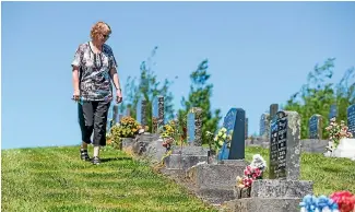  ??  ?? Inglewood’s Marie Yeates checks family members’ headstones at the town’s cemetery after vandals tipped over more than 20 on Sunday night.