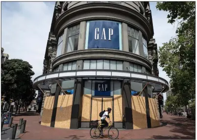  ?? (AP/Eric Risberg) ?? A cyclist passes a boarded-up and closed Gap store near Union Square in San Francisco last month.
