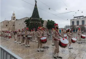  ?? AP Photo/Nasser Nasser ?? ■ Palestinia­n scout bands parade through Manger Square on Thursday at the Church of the Nativity, traditiona­lly recognized by Christians to be the birthplace of Jesus Christ, ahead of the midnight Mass, in the West Bank city of Bethlehem. Few people were there to greet them as the coronaviru­s pandemic and a strict lockdown dampened Christmas Eve celebratio­ns.