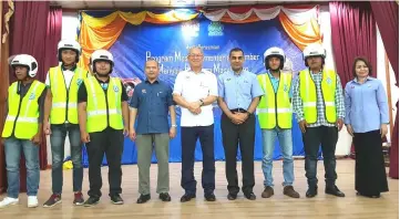  ??  ?? Riot (centre) and Mohammed Azman on his left join other local officials and the motorcycli­sts, who received brand new helmets earlier, in a group photo on stage.