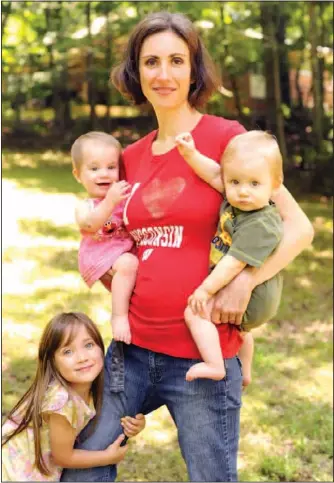  ??  ?? Mother of three Angi Rademacher holds her 11-month-old twins, from left, Seren and Crusoe, while 4-year-old Leisl, stands with them at the family’s home in Apison, Tenn. Rademacher chose to breast-feed Leisl until the age of 2 and is currently nursing...