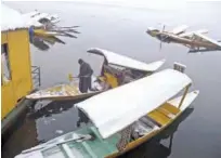  ?? Agence France-presse ?? A Kashmiri boatman clears snow from boats in Dal Lake after a fresh snowfall in Srinagar on Friday.