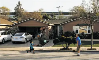  ?? Mason Trinca / Special to The Chronicle ?? Greyson (left) and Edric Yamamoto play as Apple’s campus looms behind their Sunnyvale home.