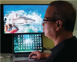  ??  ?? SHANGHAI: This picture taken on October 18, 2016 shows Chan Ming, who survived a close encounter with a great white shark while cage diving off Guadalupe Island, Mexico, watching the viral video of the great white shark on his computer.—AFP