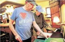  ?? Elizabeth Conley / Staff photograph­er ?? Marcel and Lynn Mason look over menus during an estate sale at the Black Labrador, a longtime English pub mainstay in Montrose that permanentl­y closed last month.