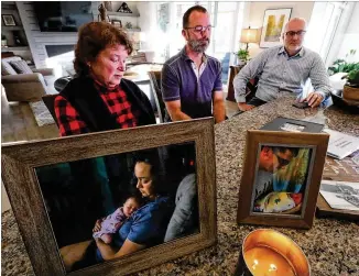  ?? CURTIS COMPTON / CCOMPTON@AJC.COM ?? A candle burns last month near a photo of Kaitlin Hunt and her baby, Riley, fatally struck in 2017 in Woodstock. “It’s hard to figure out how we even made it through,” said Kaitlin’s dad, Gregg Vandiver (center), shown with her mom, Kathy Vandiver, and Gregg’s partner, David Lickman, in Woodstock.