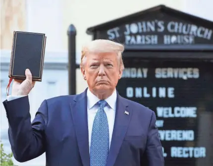  ?? PATRICK SEMANSKY/AP ?? President Donald Trump holds up a Bible on June 1 in a photo op outside St. John’s Church across Lafayette Square from the White House, the day after the historic church was damaged by fire during protests.