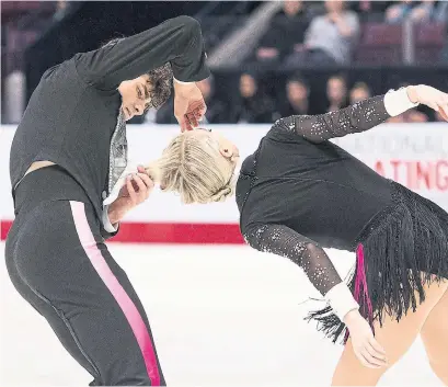  ?? NATHAN DENETTE THE CANADIAN PRESS ?? Ice dancer Paul Poirier works on a wardrobe malfunctio­n of sorts after partner Piper Gilles’ hair got stuck on a jacket button during Friday’s competitio­n at the Canadian figure skating championsh­ips. Despite getting tangled, the ice dance duo is in the lead.