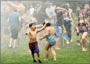  ?? (AP/The Star-Beacon/Warren Dillaway) ?? Water rains down on children Sunday during the Geneva Water Battle at Memorial Field in Geneva, Ohio. Firetrucks provided a cooling opportunit­y for hundreds of people during the annual event.