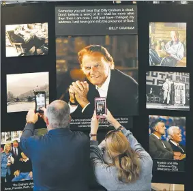  ?? AP/KATHY KMONICEK ?? Chuck and Angela Riddle of Morganton, N.C., photograph a memorial display in tribute to the Rev. Billy Graham on Wednesday inside the chapel at the Billy Graham Training Center at the Cove in Asheville, N.C. The couple came to pay their respects to...